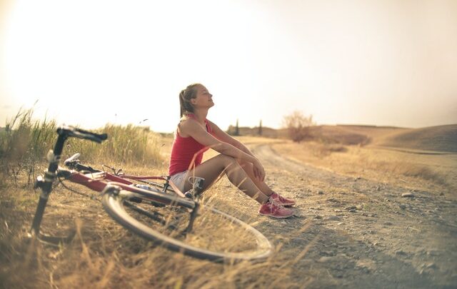 Femme assise à côté de son vélo dans un pré